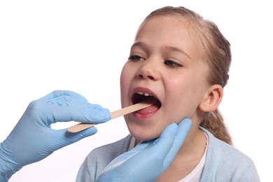 Doctor examining girl`s oral cavity with tongue depressor on white background