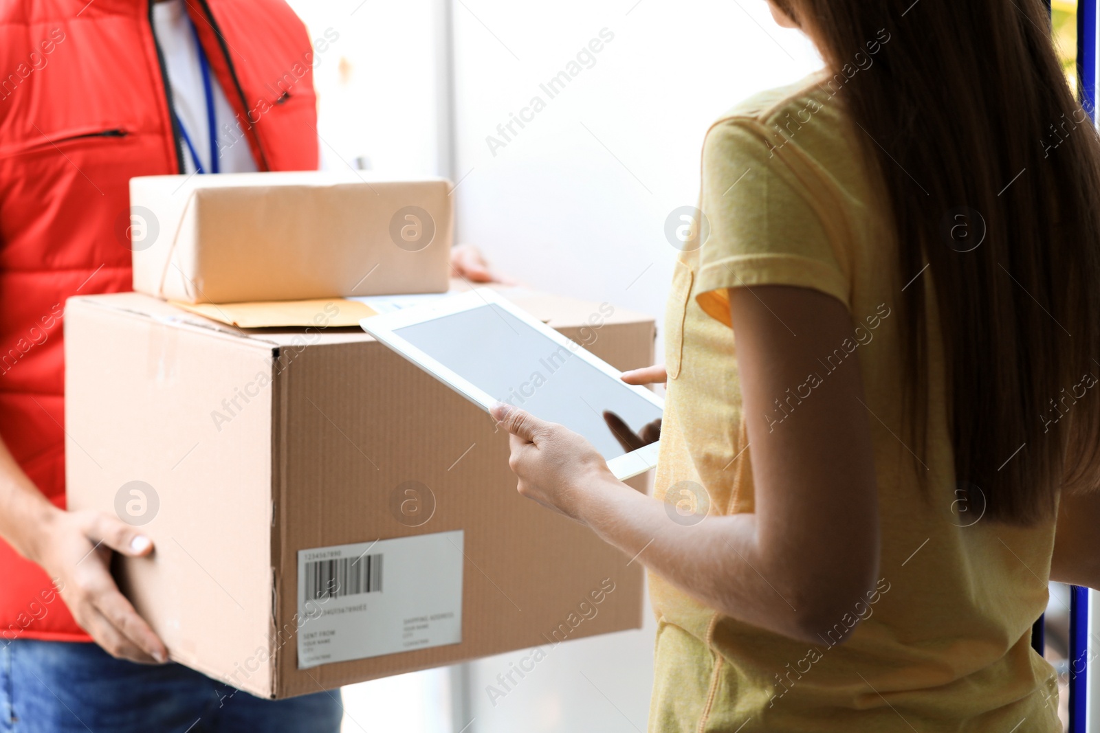 Photo of Woman using app to confirm delivery of parcel from courier on doorstep, closeup