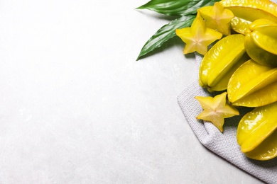 Photo of Cut and whole carambolas with green leaves on light table, above view. Space for text