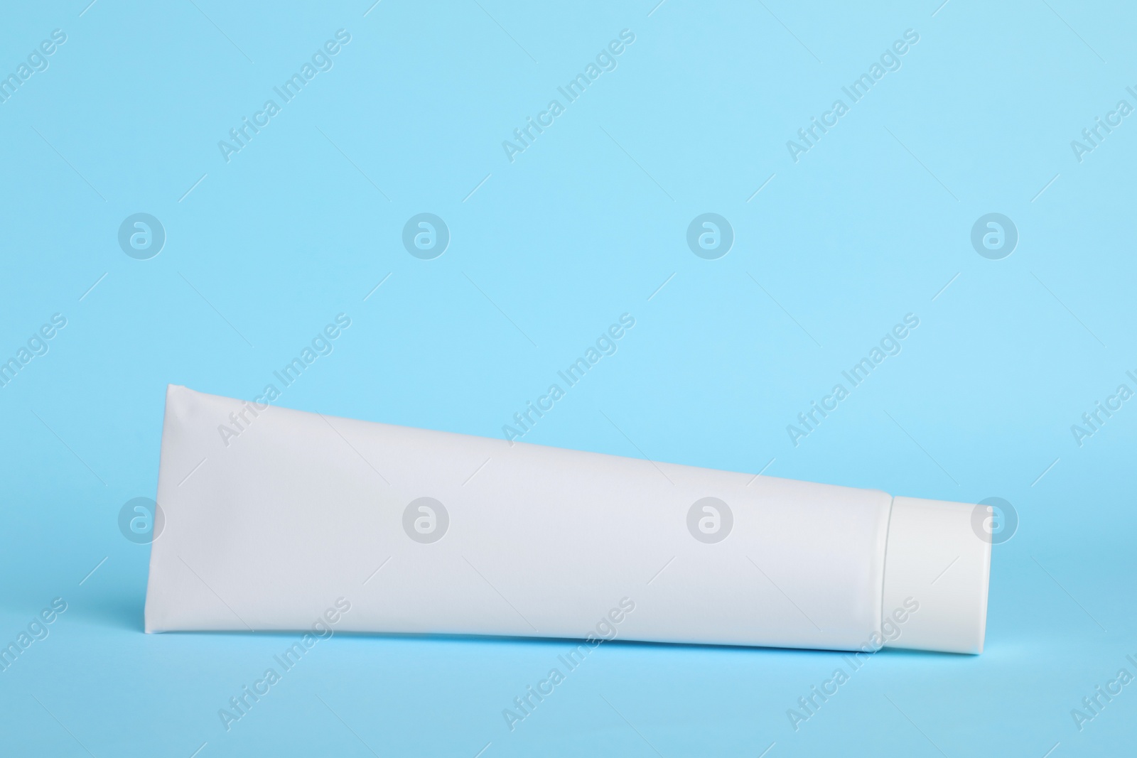 Photo of Blank tube of toothpaste on light blue background. Space for text