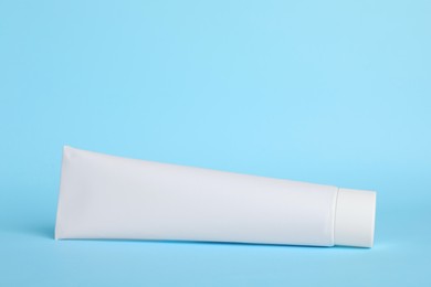 Photo of Blank tube of toothpaste on light blue background. Space for text