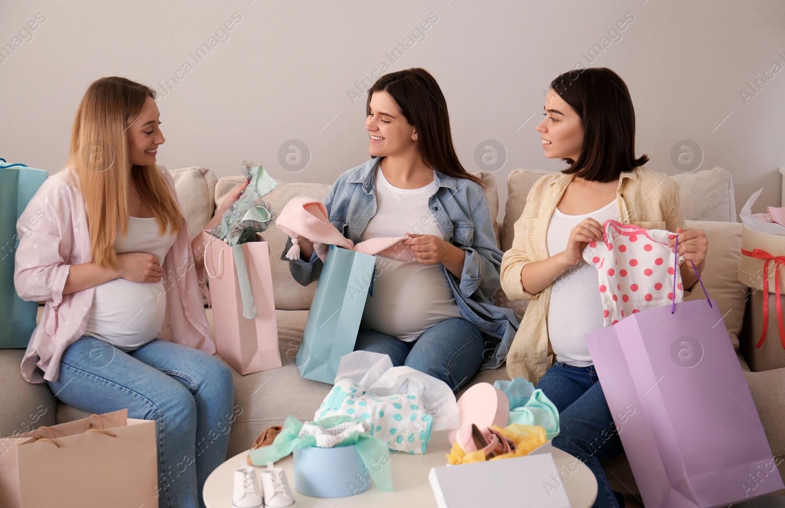 Photo of Happy pregnant women spending time together in living room after shopping