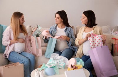 Happy pregnant women spending time together in living room after shopping