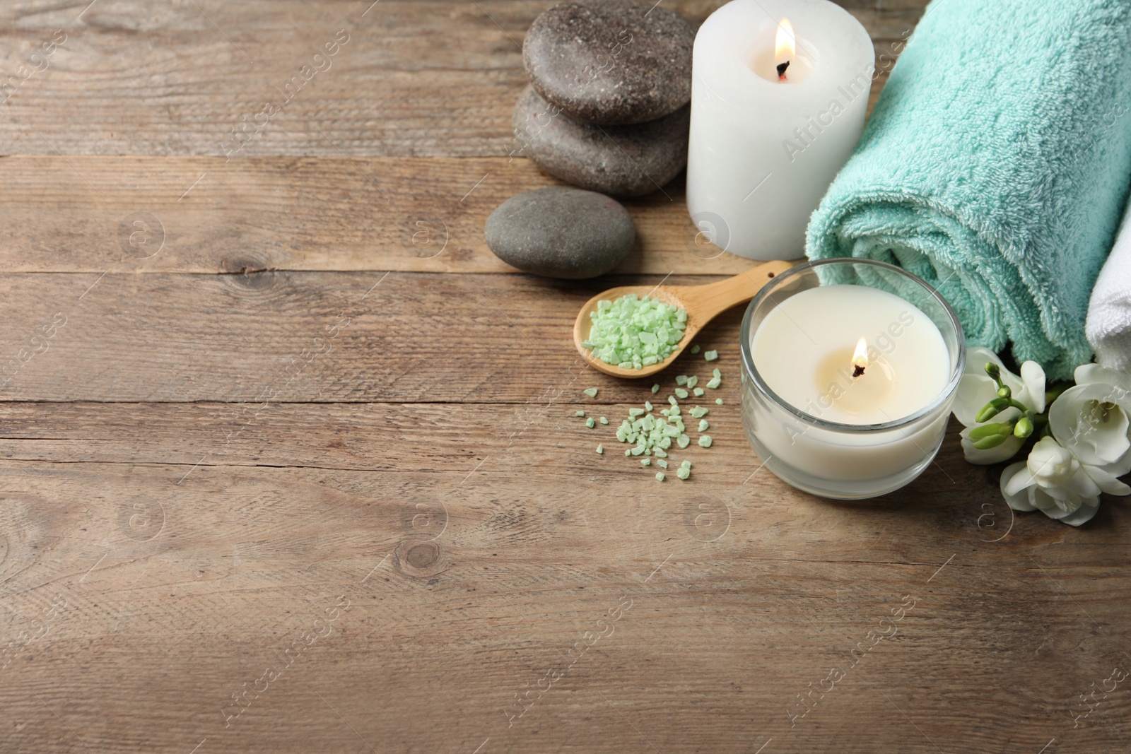 Photo of Beautiful composition with burning candles and different spa products on wooden table. Space for text