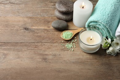 Beautiful composition with burning candles and different spa products on wooden table. Space for text
