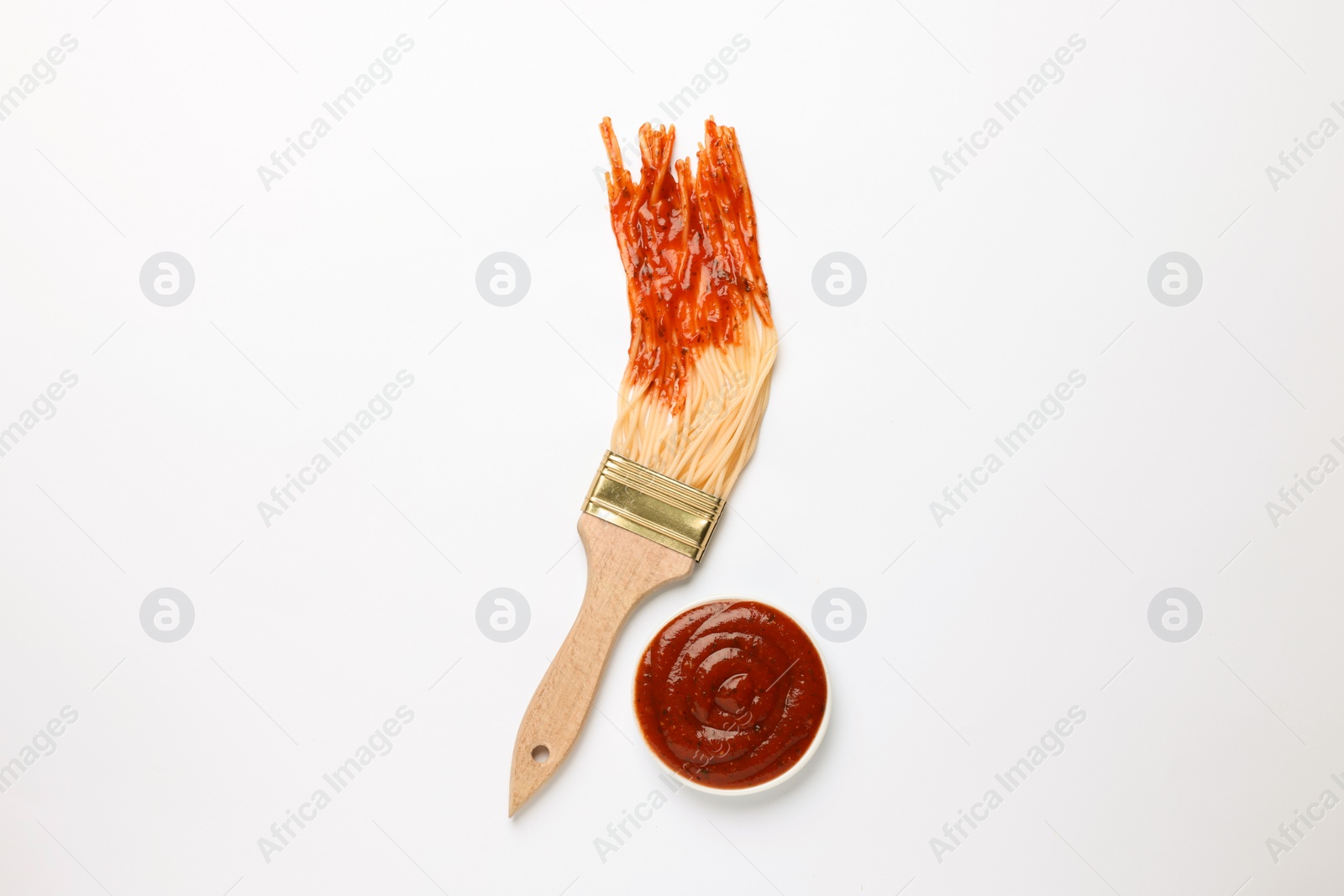 Photo of Brush painting with spaghetti dipped in ketchup on white background, top view. Creative concept