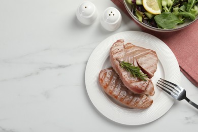 Delicious tuna steaks with rosemary and salad served on white marble table, flat lay. Space for text