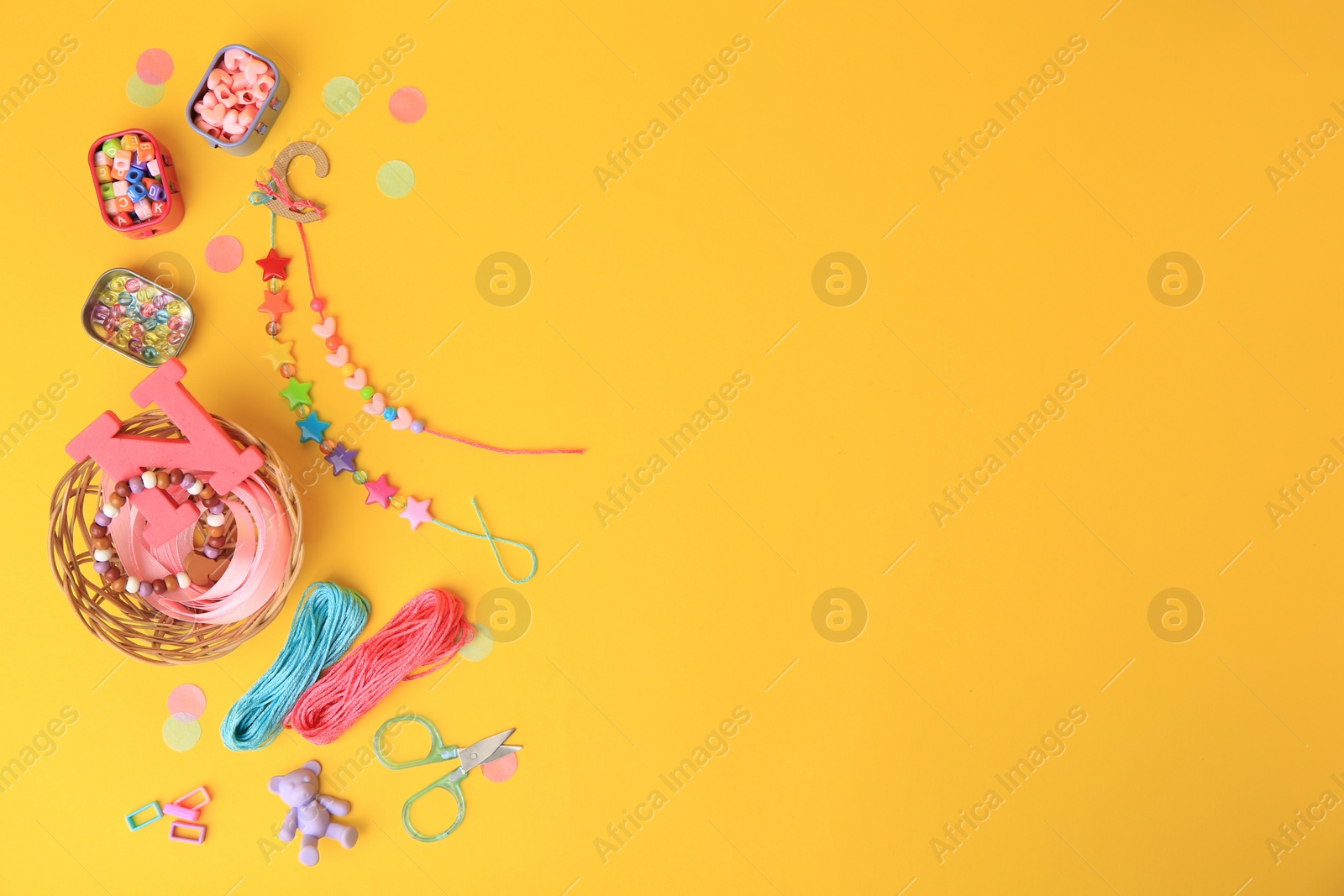 Photo of Kid`s handmade jewelry kit. Colorful beads, bracelets and different supplies on orange background, flat lay. Space for text