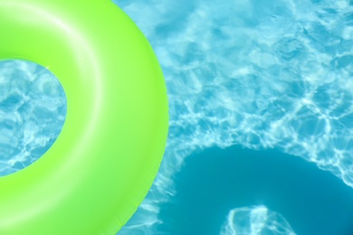 Bright inflatable ring floating in swimming pool on sunny day. Space for text