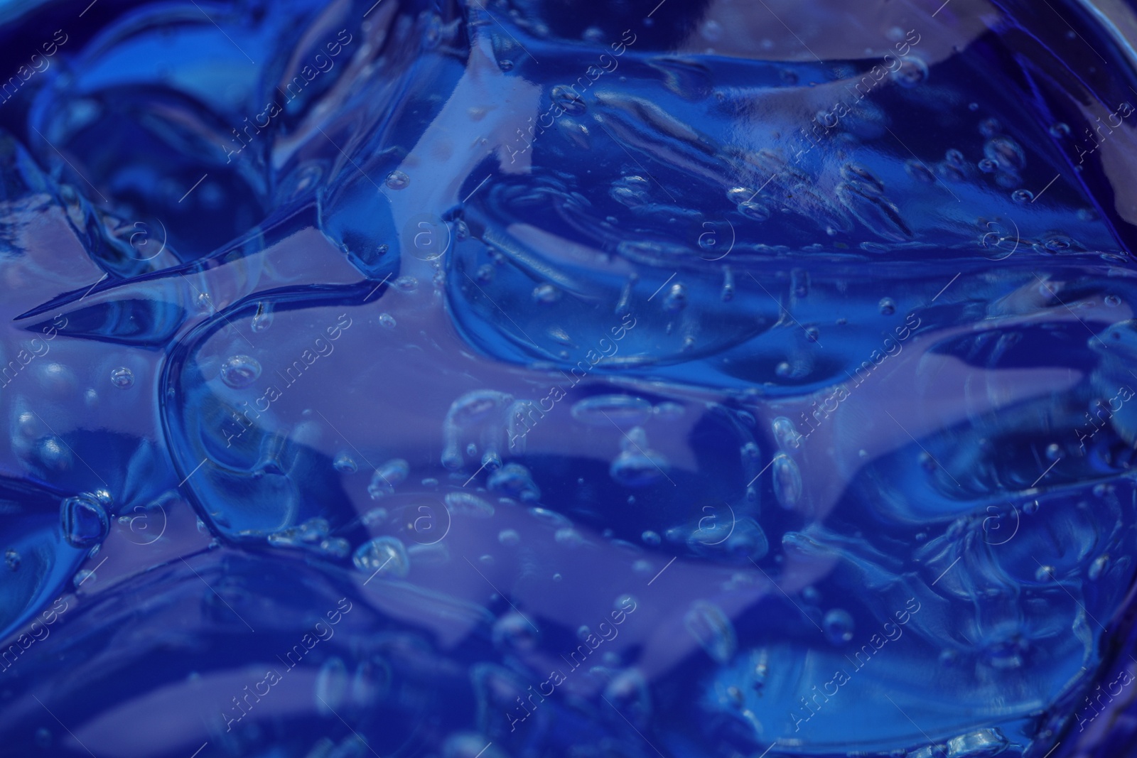 Photo of Pure transparent cosmetic gel on blue background, closeup