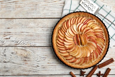 Photo of Delicious homemade apple tart, cinnamon, anise and cake shovel on white wooden table, flat lay. Space for text