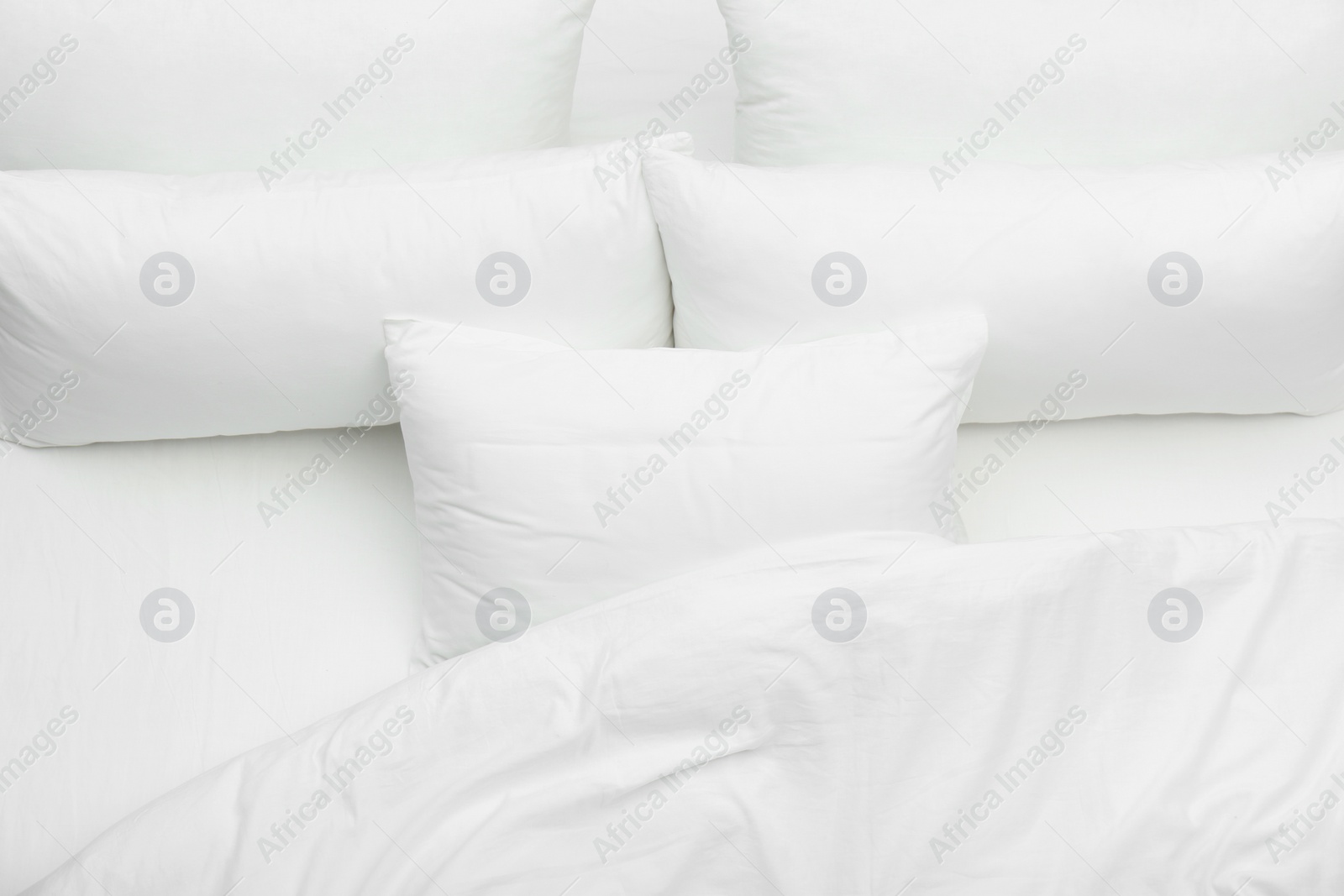 Photo of Soft white pillows and blanket on bed, top view