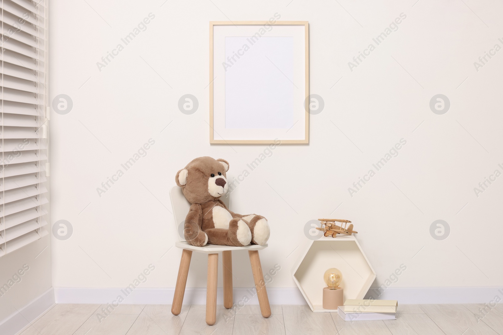 Photo of Beautiful children's room with light wall, furniture and toys. Interior design