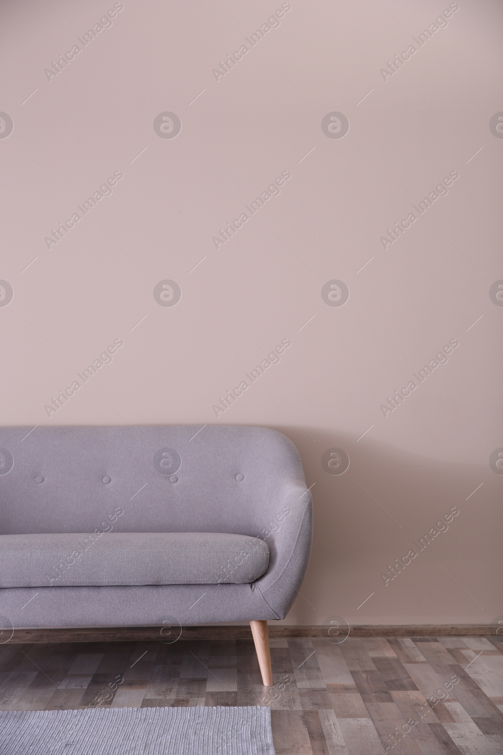 Photo of Simple living room interior with comfortable sofa near color wall. Copy space text