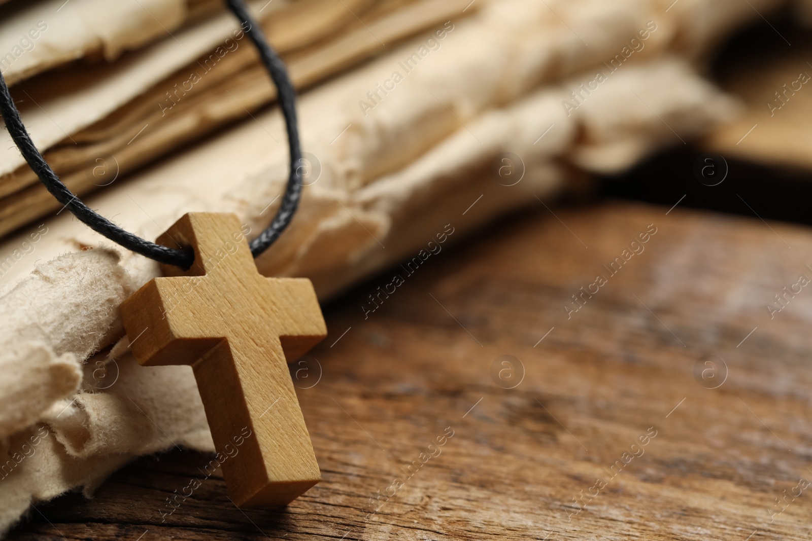 Photo of Wooden Christian cross and old Bible on table, closeup. Space for text