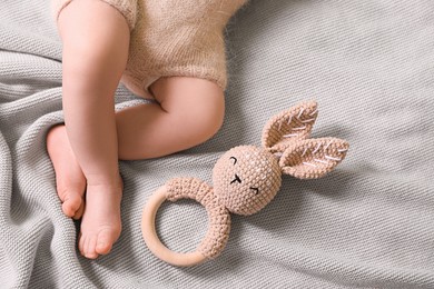 Photo of Cute newborn baby with toy bunny lying on light grey knitted plaid, top view. Space for text