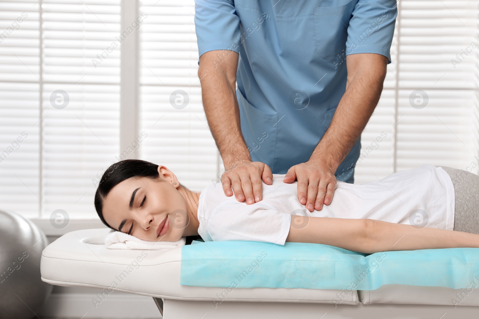 Photo of Orthopedist massaging young woman's back in clinic, closeup. Scoliosis treatment