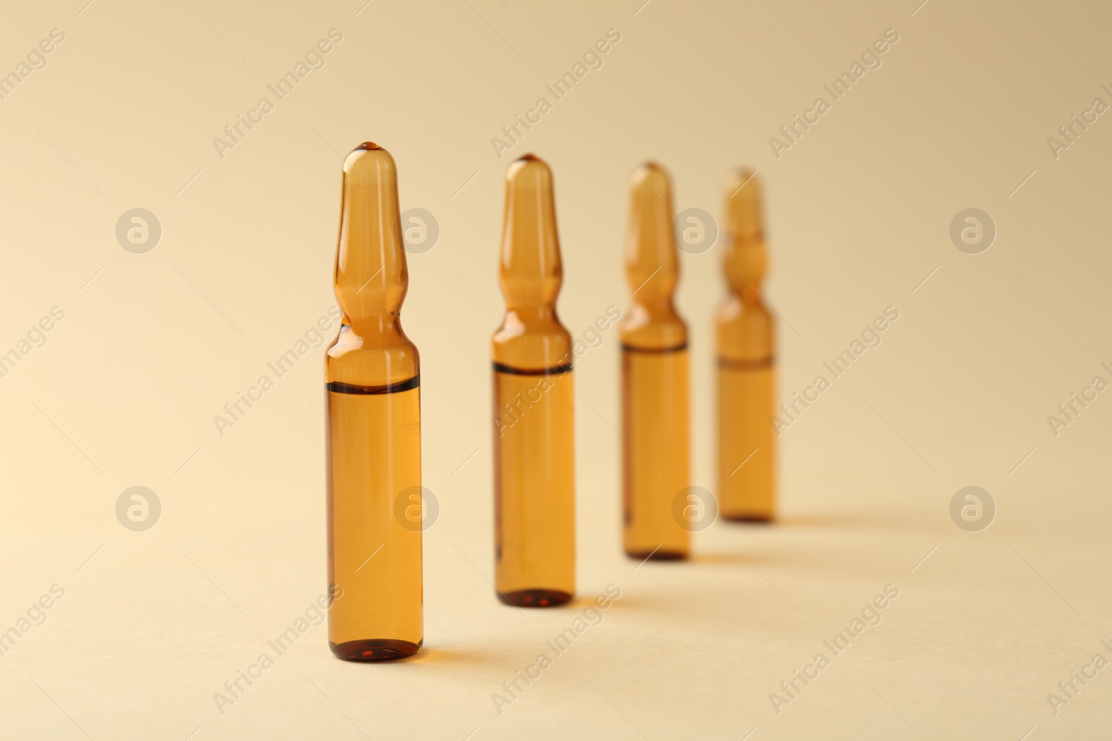 Photo of Glass ampoules with liquid on beige background