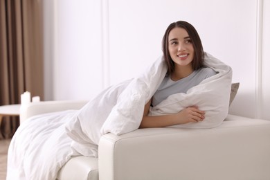 Woman covered in blanket resting on sofa, space for text