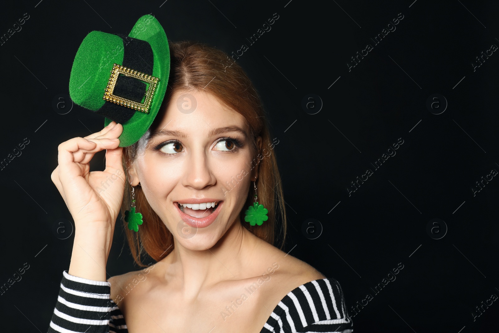 Photo of Young woman with green leprechaun hat on black background, space for text. St. Patrick's Day celebration