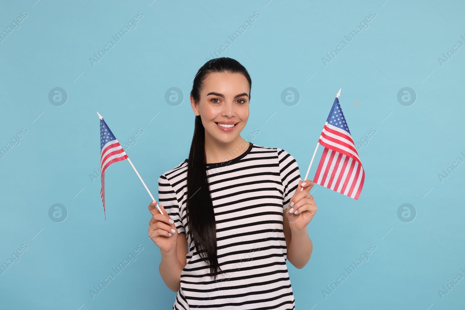 Photo of 4th of July - Independence Day of USA. Happy woman with American flags on light blue background