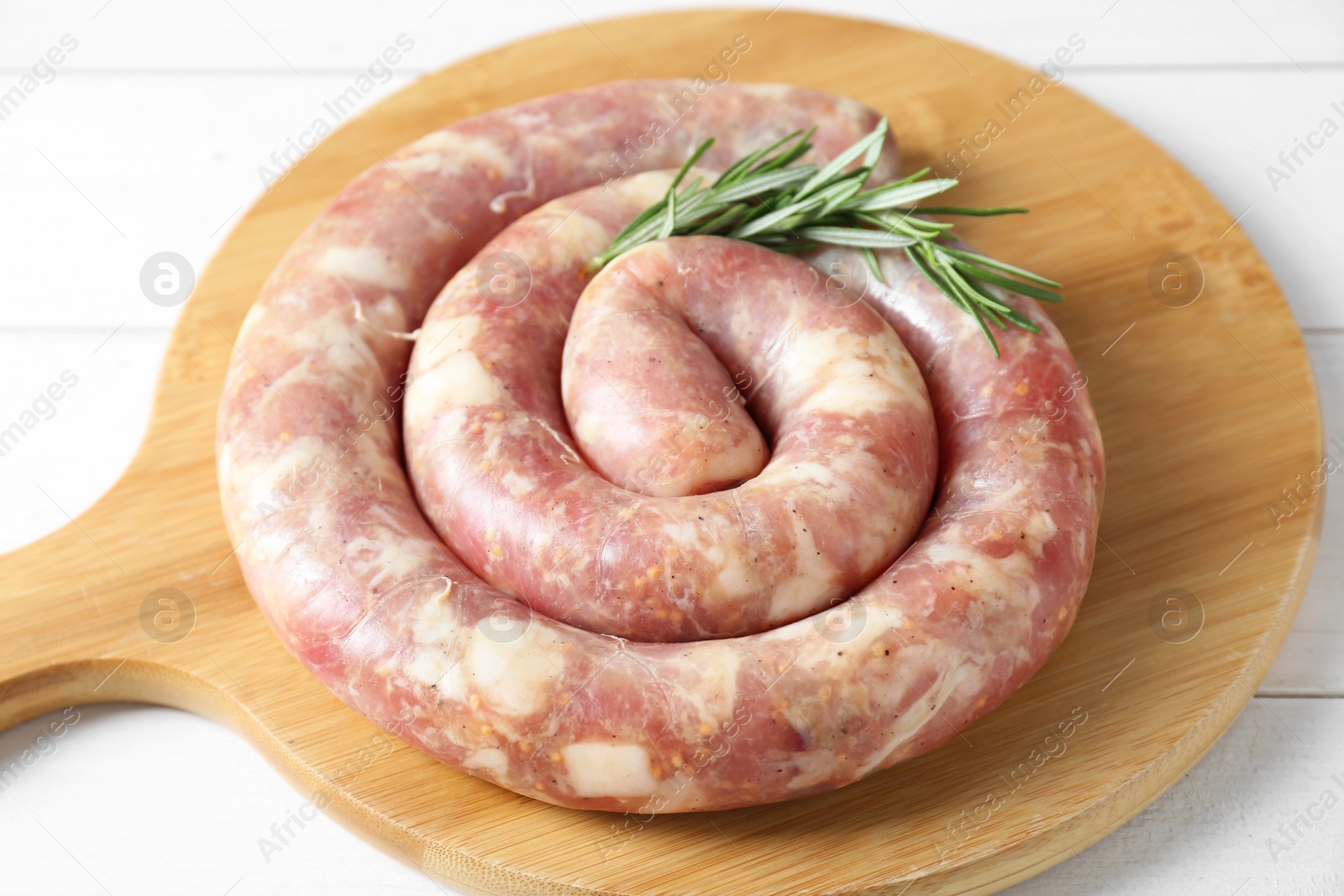 Photo of Raw homemade sausage and rosemary on white wooden table, closeup