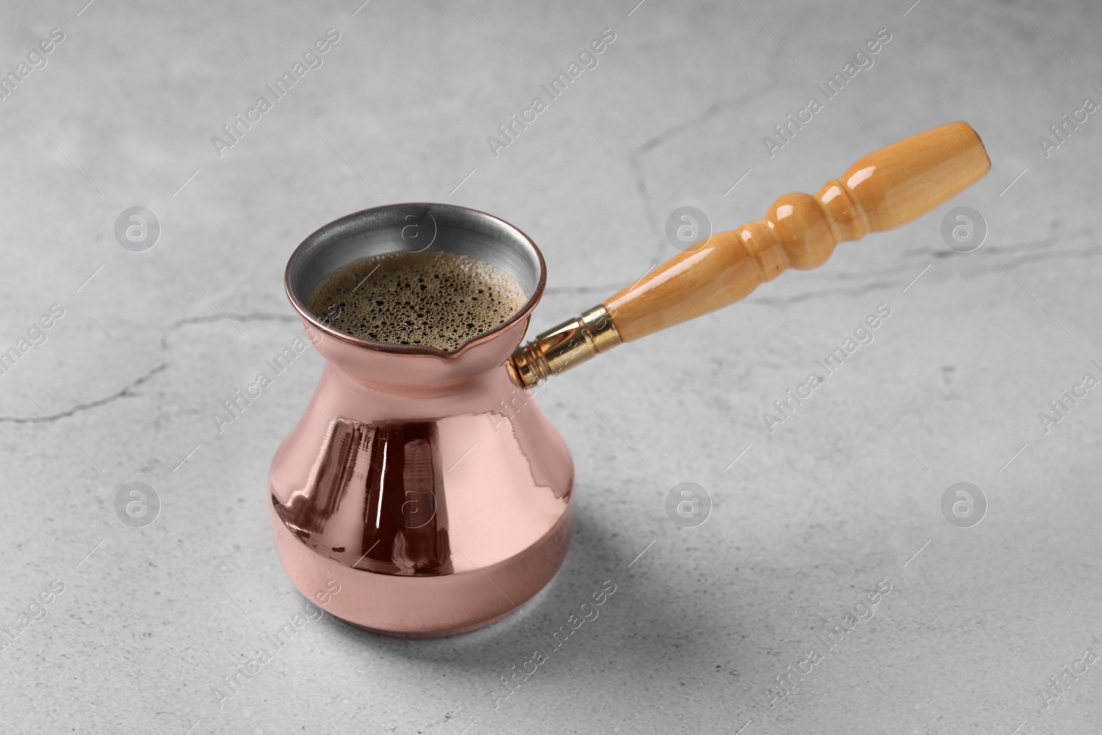 Photo of Turkish coffee in cezve on light grey table