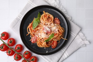 Tasty pasta with tomato sauce, cheese and basil on white tiled table, flat lay