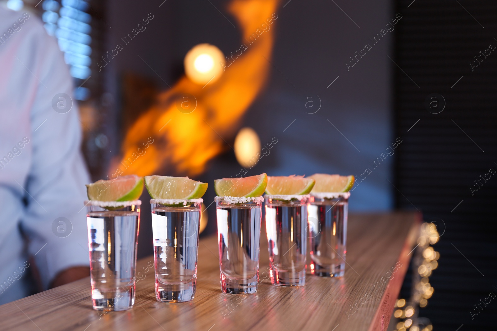 Photo of Mexican Tequila shots with lime slices on bar counter