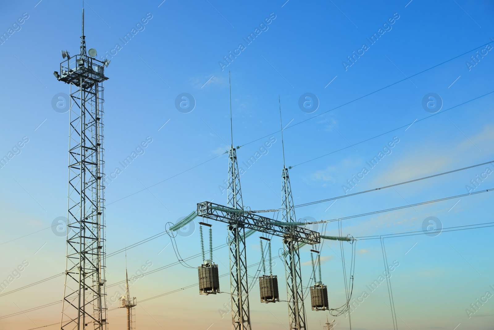 Photo of High voltage towers against blue sky on sunny day