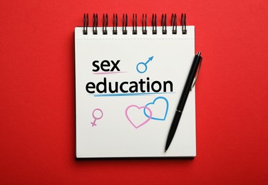 Image of Notebook with text Sex Education, hearts, female and male gender signs on red background, top view