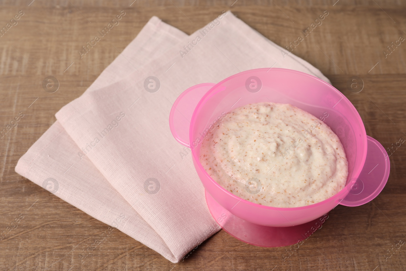 Photo of Baby food. Puree in bowl on wooden table