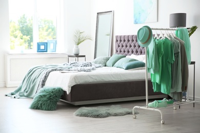 Photo of Stylish bedroom interior with clothes rack and mint decor elements