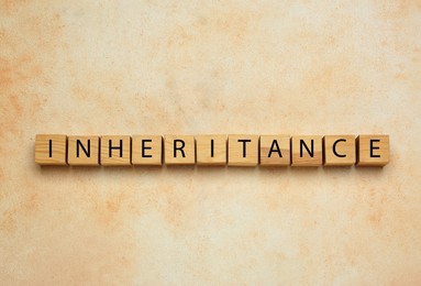 Photo of Word Inheritance made with wooden cubes on beige background, flat lay