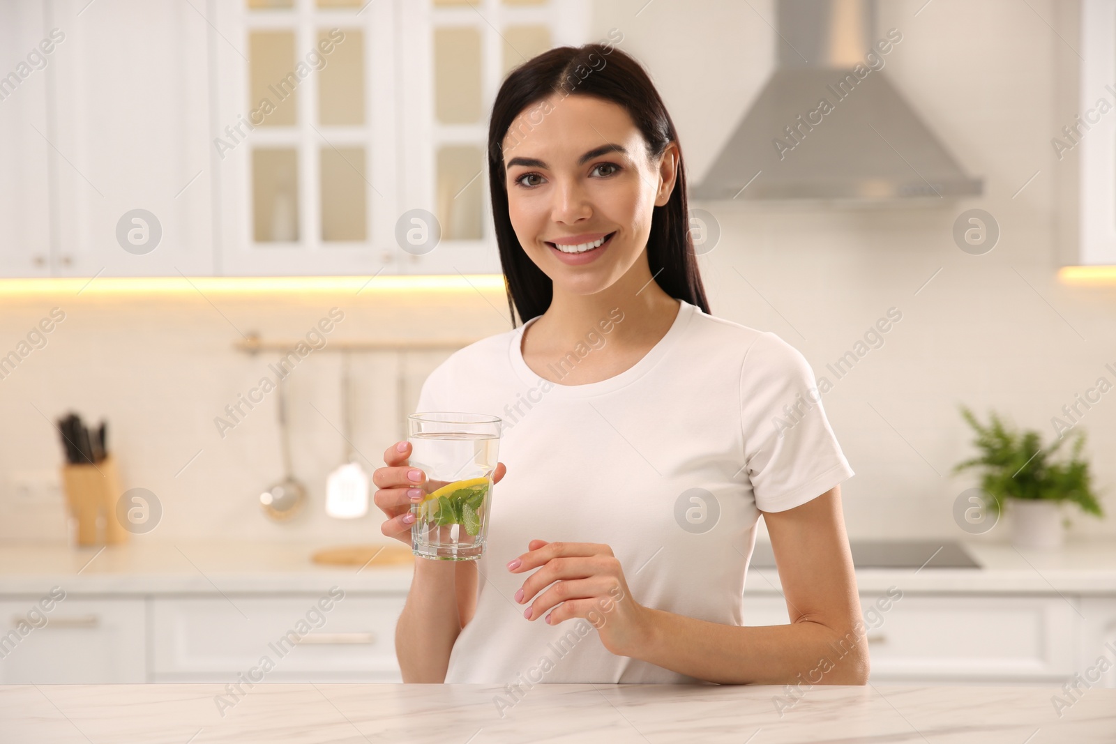 Photo of Young woman with glass of fresh lemonade at home