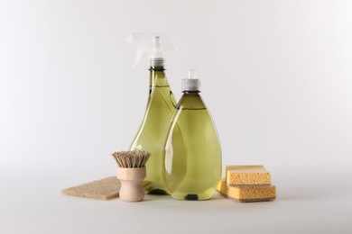 Photo of Bottles of cleaning product, brush and sponges isolated on white