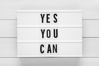 Photo of Lightbox with phrase Yes You Can on white wooden table, top view. Motivational quote