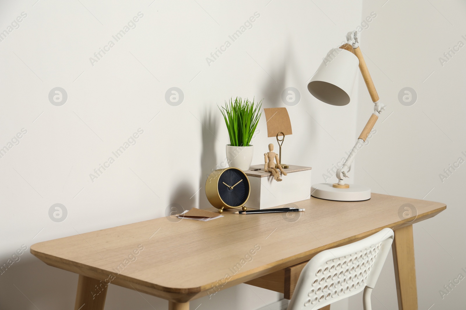 Photo of Comfortable workplace with wooden desk near white wall