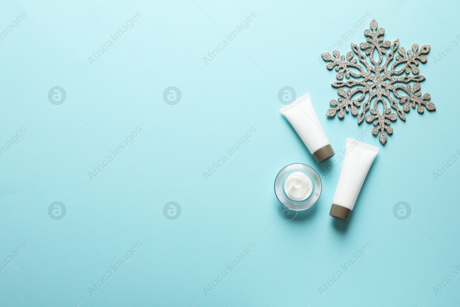 Photo of Set of cosmetic products on blue background, flat lay with space for text. Winter care