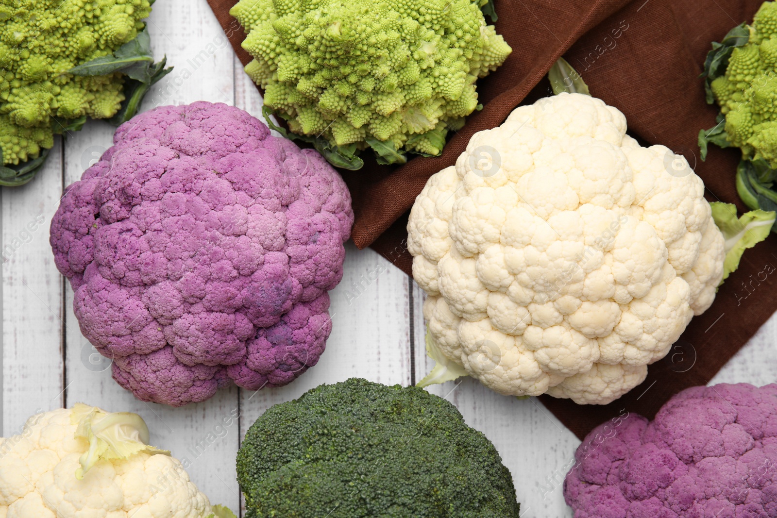 Photo of Different fresh cabbages on white wooden table, flat lay