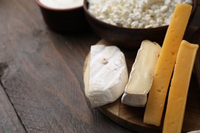 Photo of Dairy products. Different kinds of cheese on wooden table, closeup. Space for text