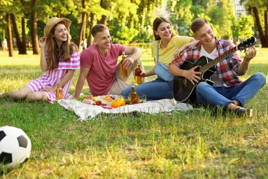 Photo of Young people enjoying picnic in park on summer day