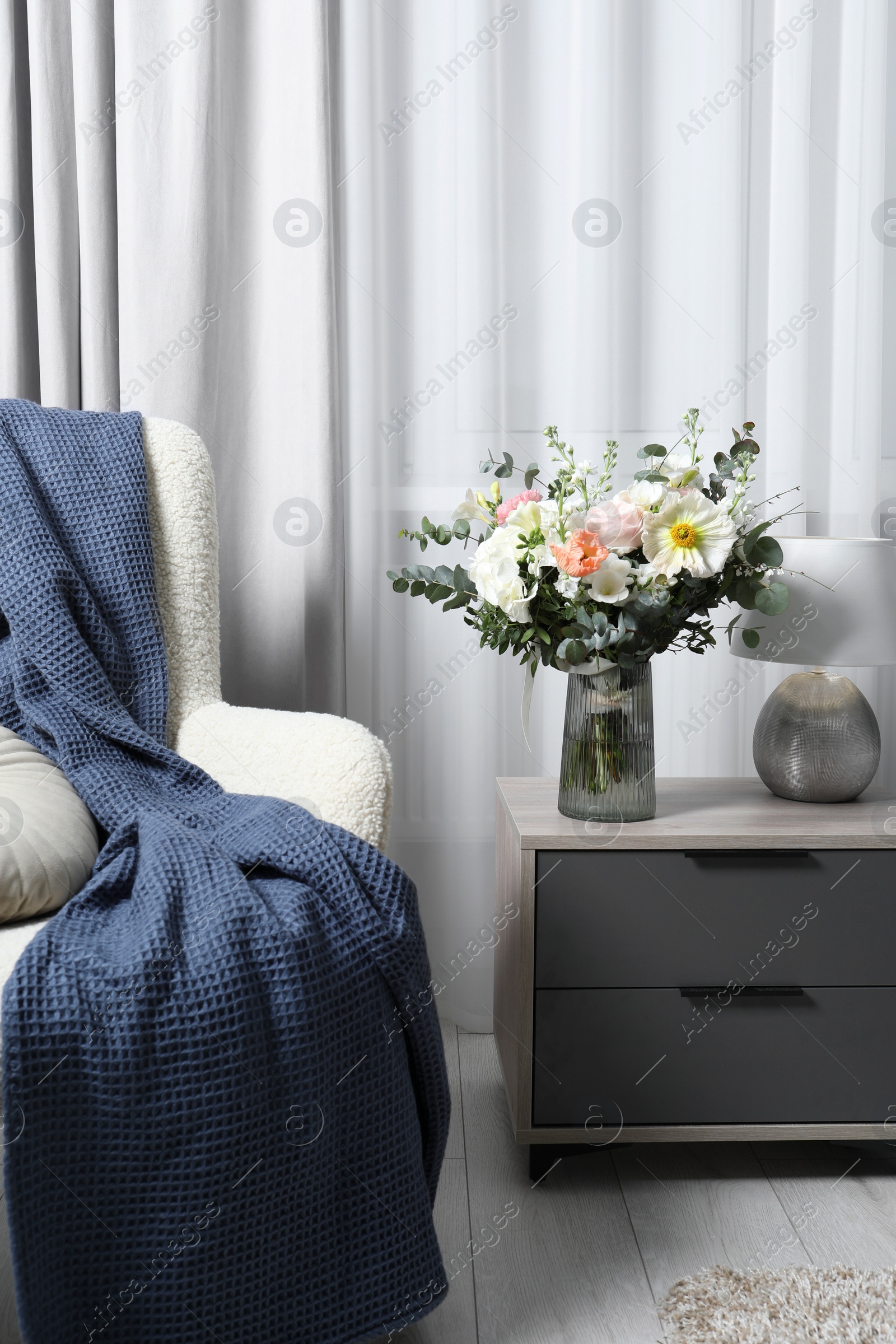 Photo of Bouquet of beautiful flowers near armchair indoors