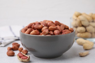 Photo of Fresh unpeeled peanuts in bowl on grey table, closeup