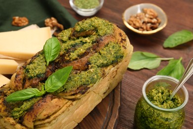Photo of Freshly baked pesto bread with basil and cheese on wooden table, closeup