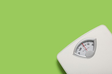 Photo of Bathroom scale on light green background, top view. Space for text