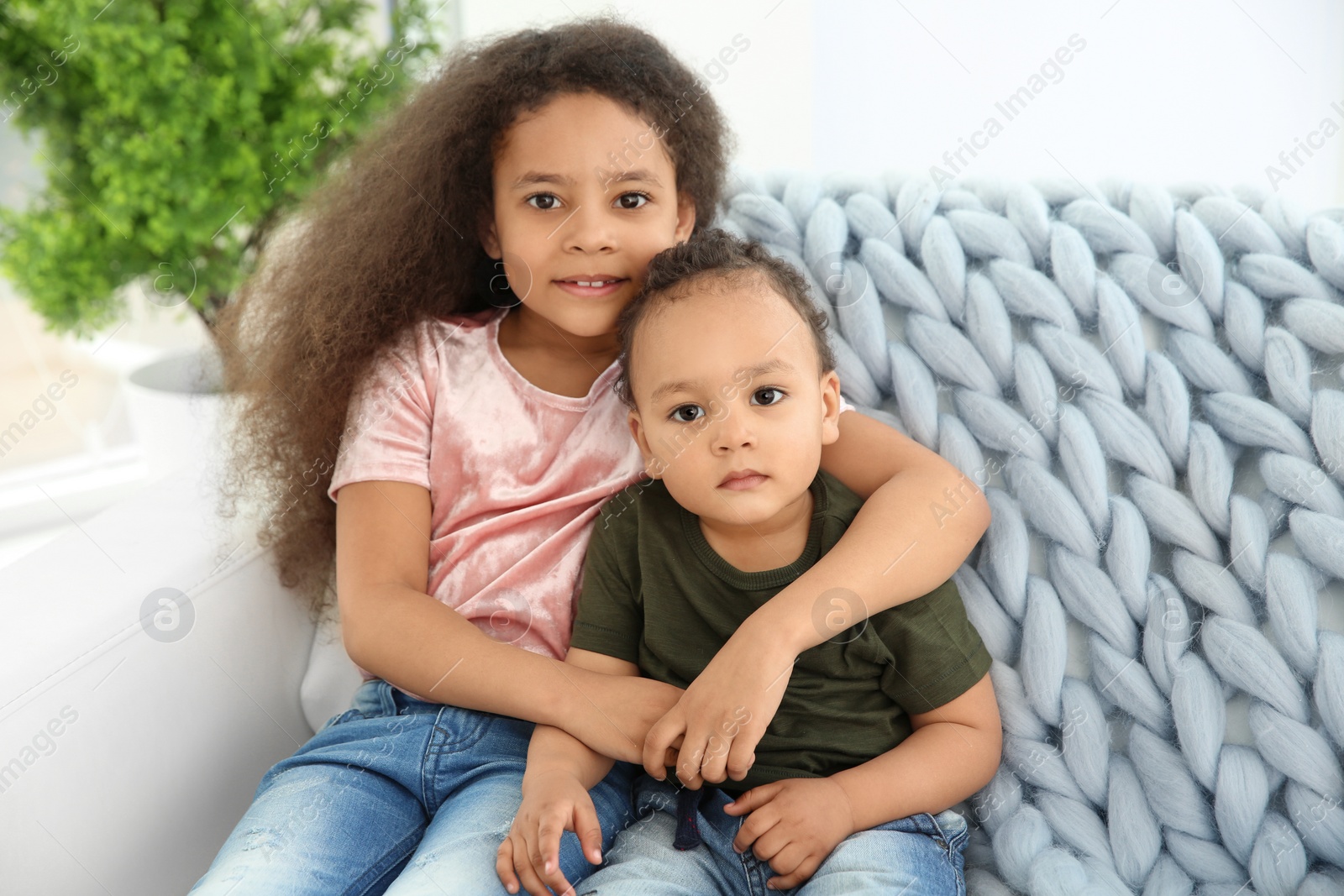 Photo of Cute African-American girl with her baby brother on couch indoors. Happy family