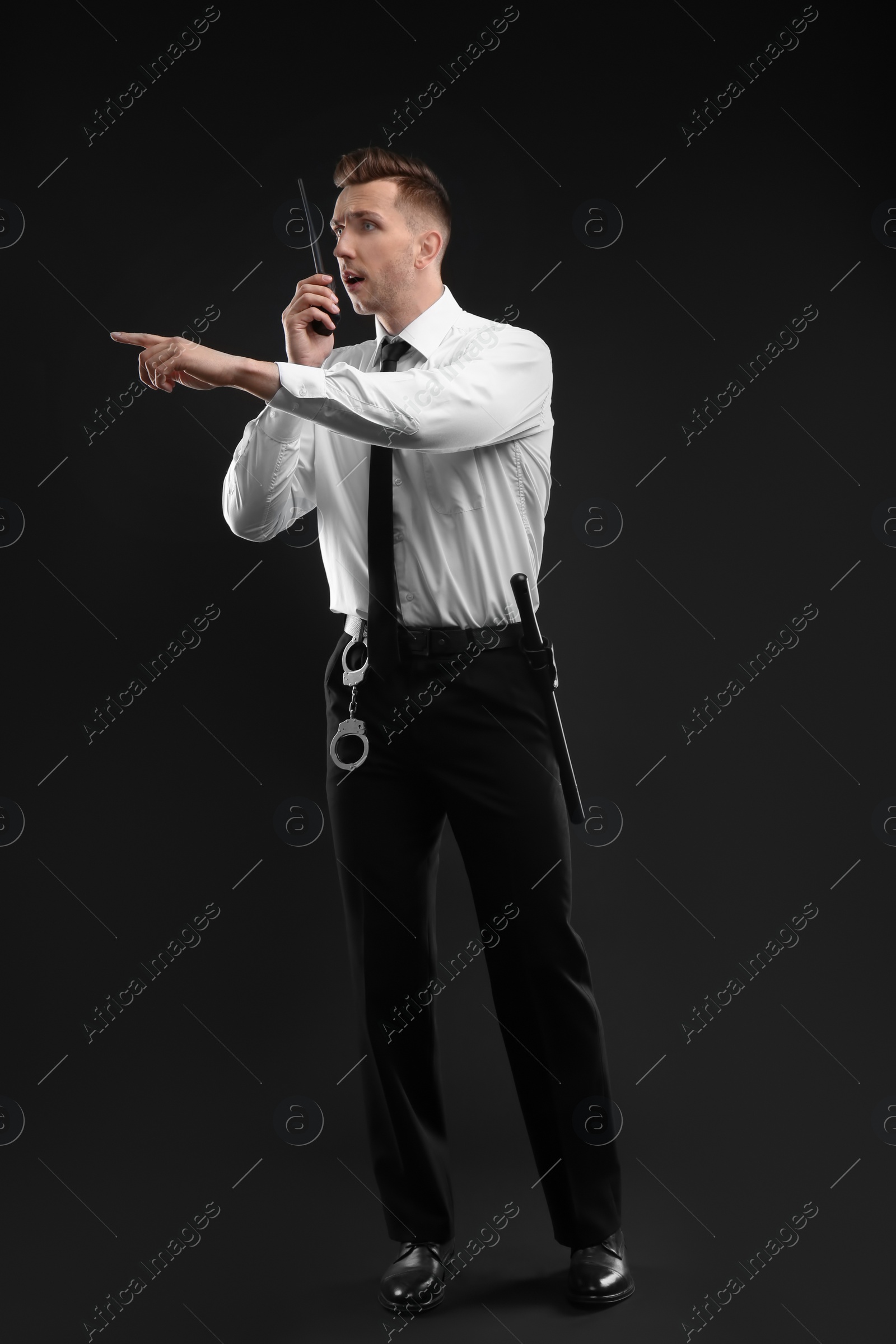 Photo of Male security guard using portable radio transmitter on dark background