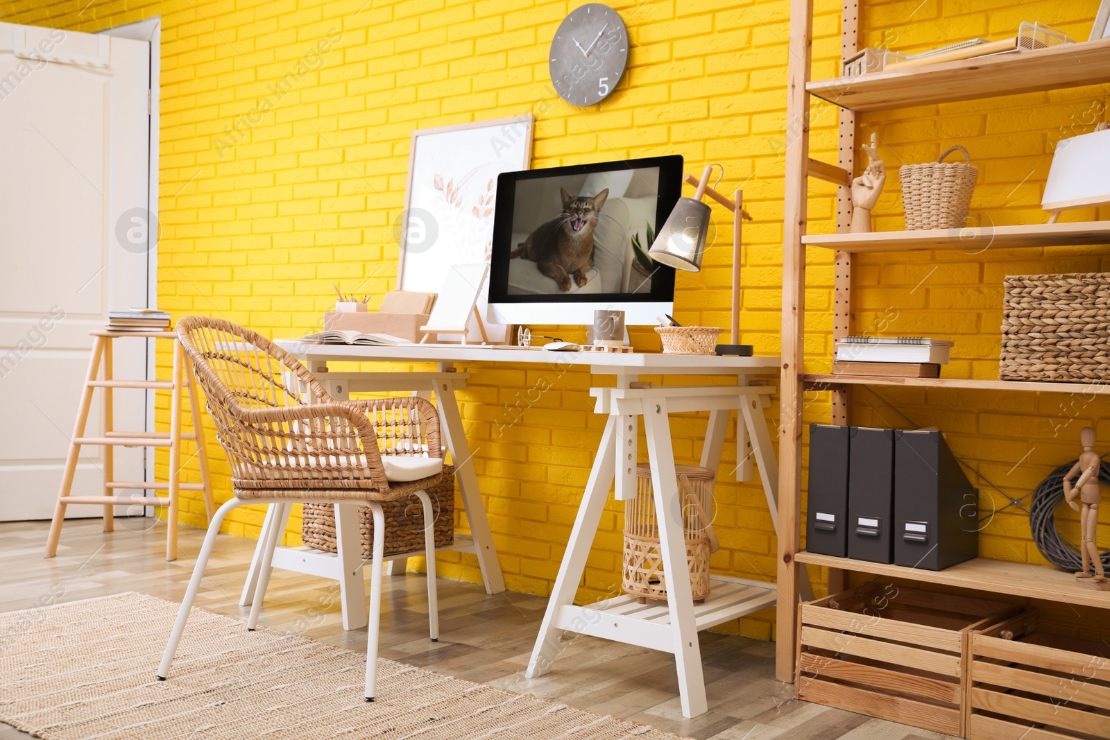 Photo of Stylish home office interior with comfortable workplace near yellow brick wall