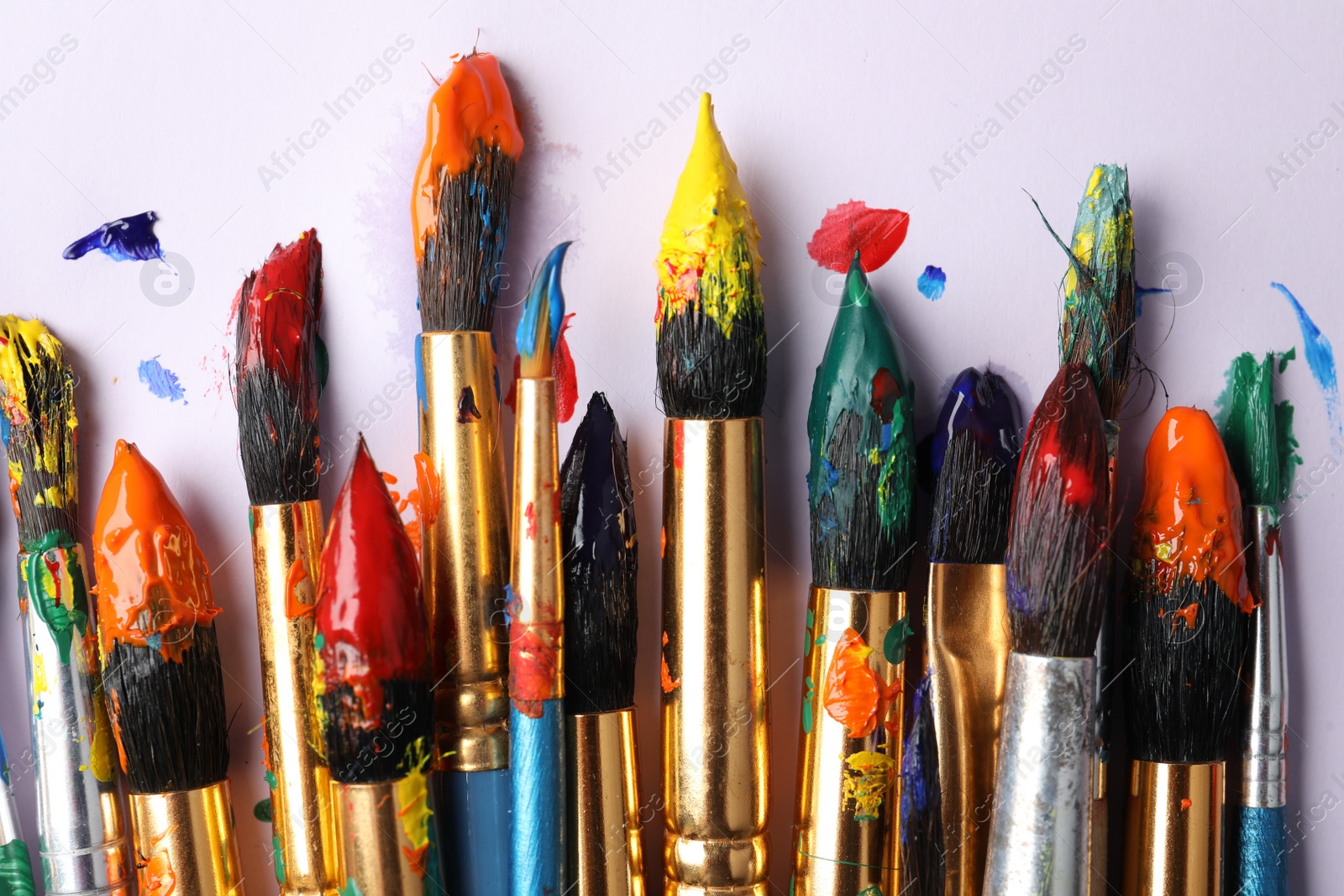 Photo of Brushes with colorful paints on white background, flat lay